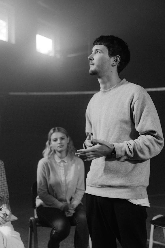 Grayscale Photo of a Man Talking in a Group